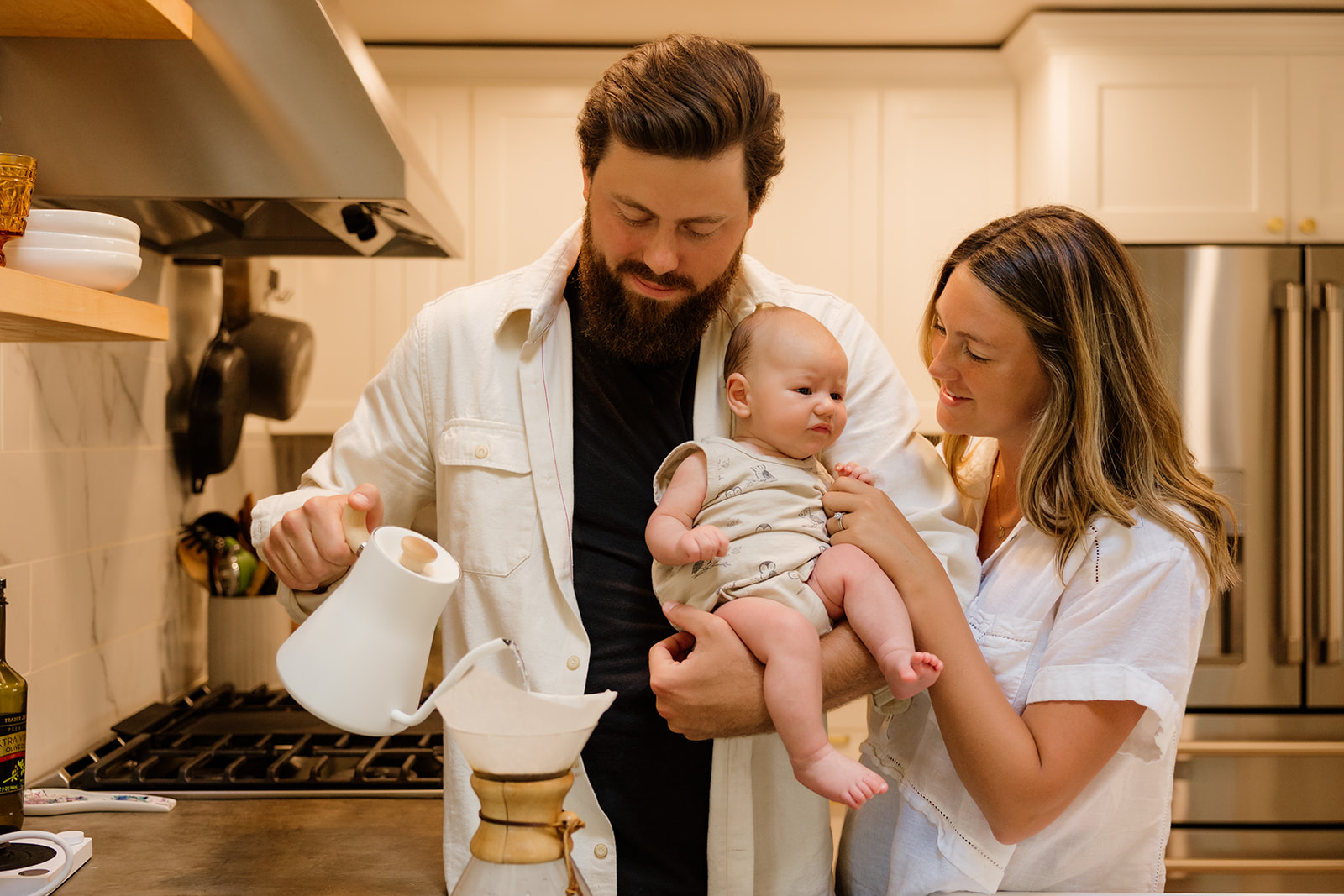 Cozy and intimate photo of a mother and father carrying their newborn baby inside their cozy Seattle kitchen.