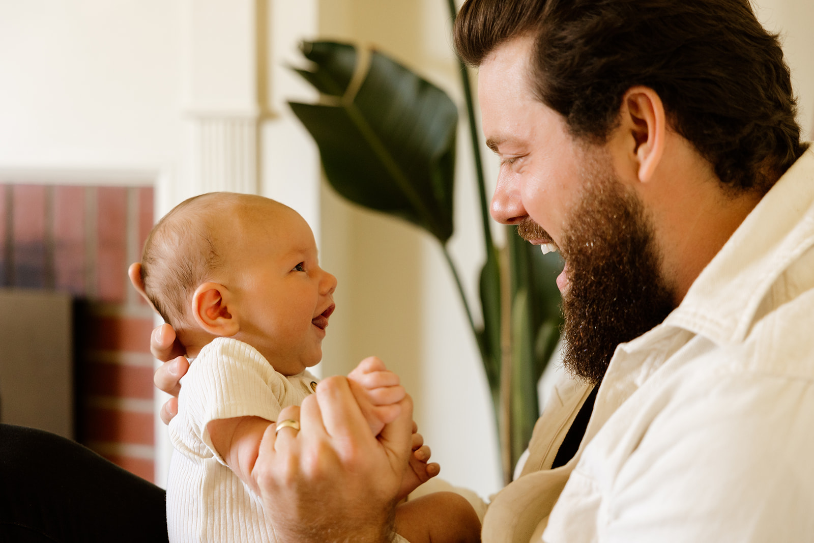 Close-up photo of a father holding his newborn baby and making the infant laugh.