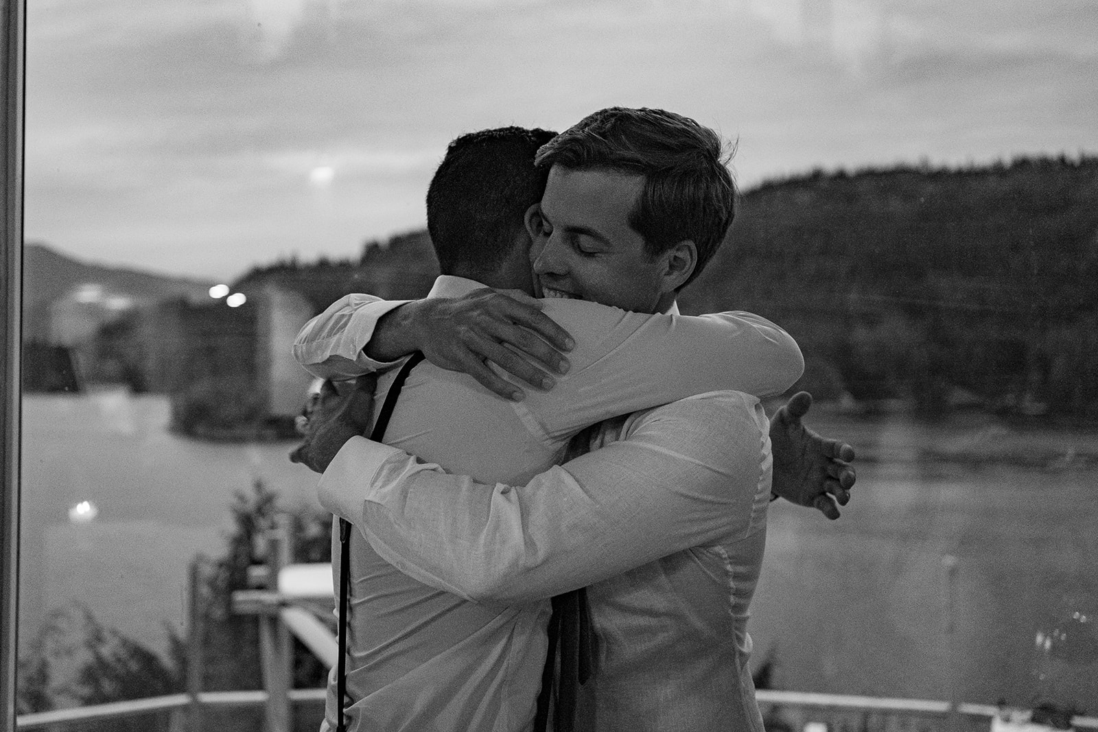 Groom hugs friend at west coast wilderness lodge wedding overlooking skookumchuk narrows on BC's sunshine coast