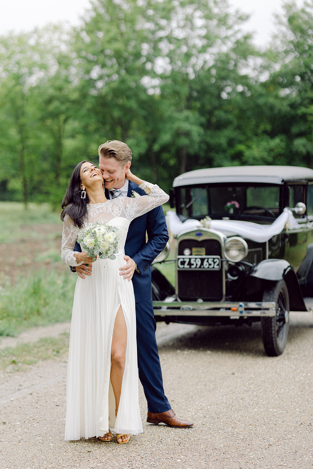 couple sitting at the back of the vintage car and smiling, kissing.