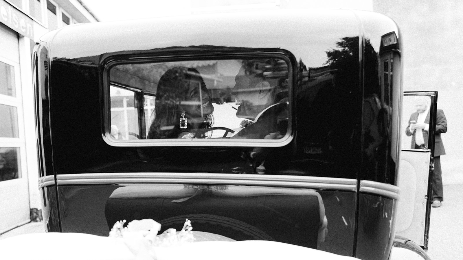 couple sitting at the back of the vintage car and smiling, kissing