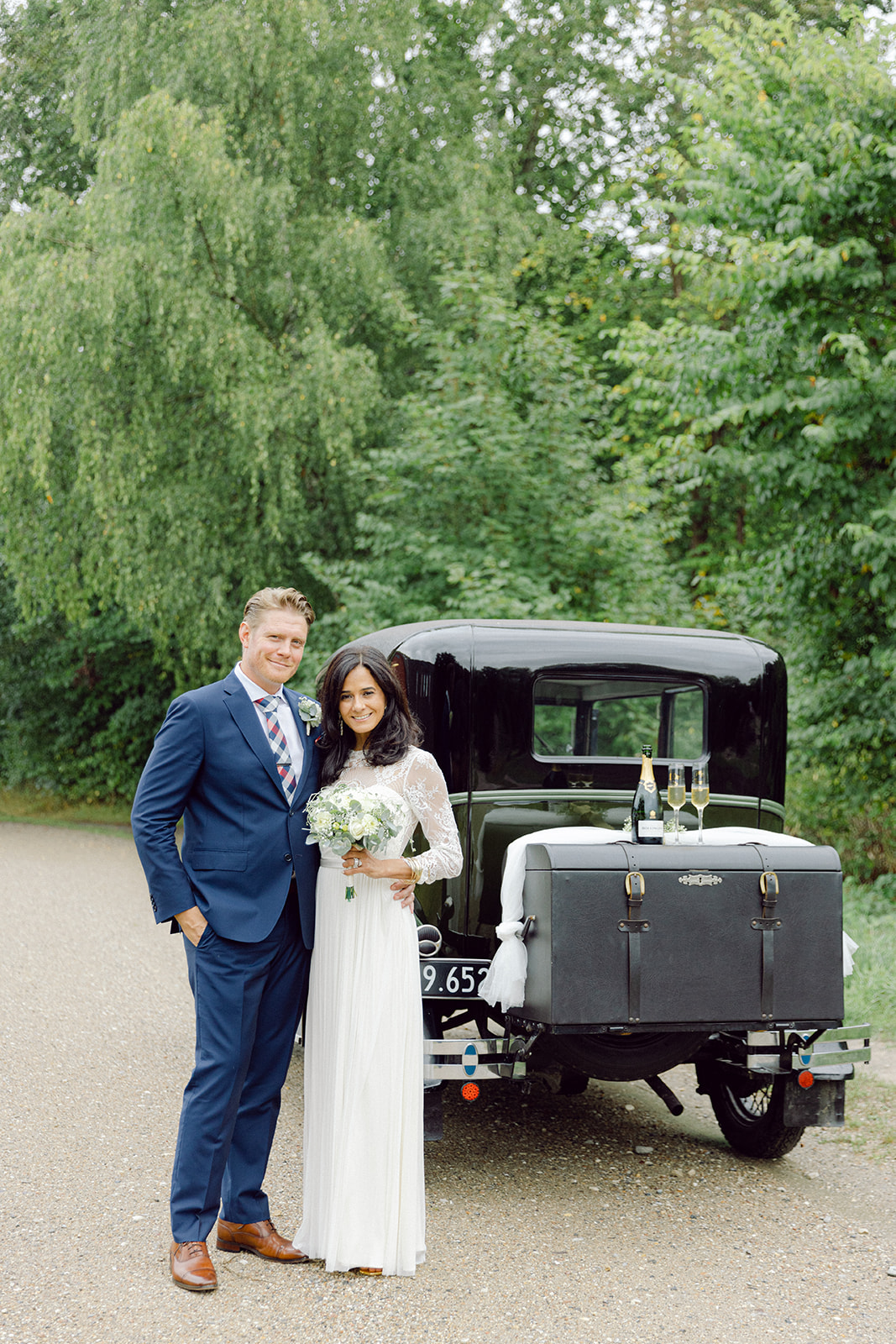 couple sitting at the back of the vintage car and smiling, kissing
