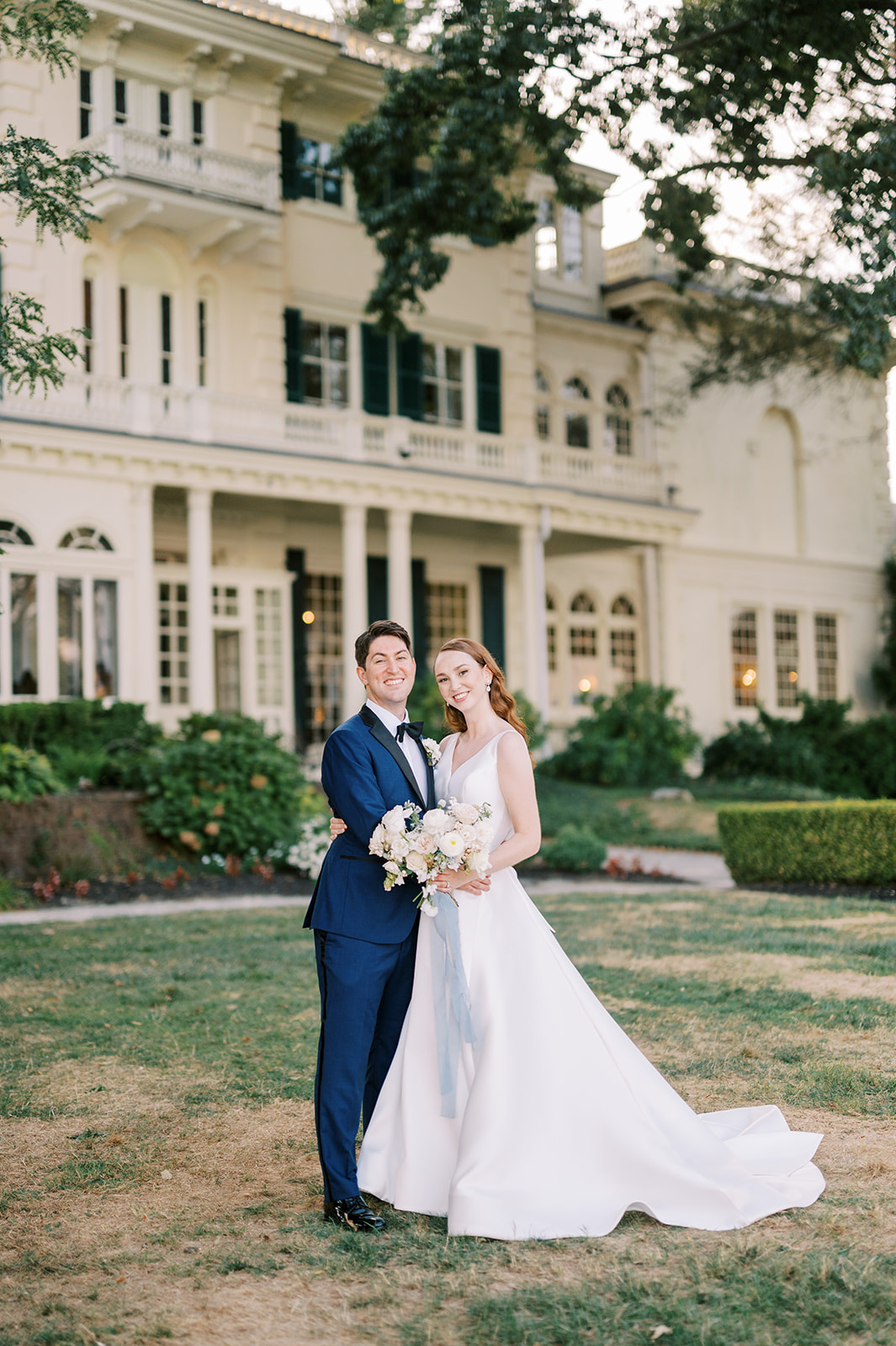 bride and groom stand on lawn in front of Timeless Garden Wedding at Historic Glen Foerd Estate in Philadelphia, PA
