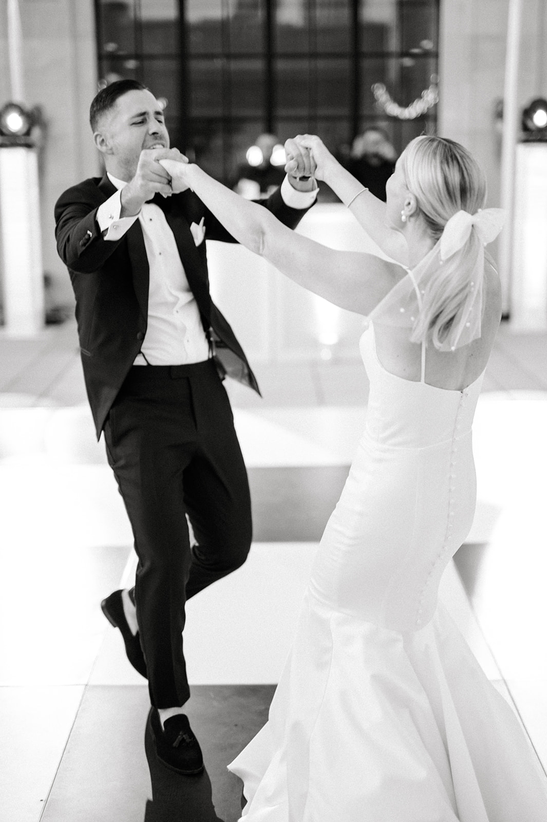 black and white photo of bride and groom dancing with excitement at Free Library of Philadelphia wedding