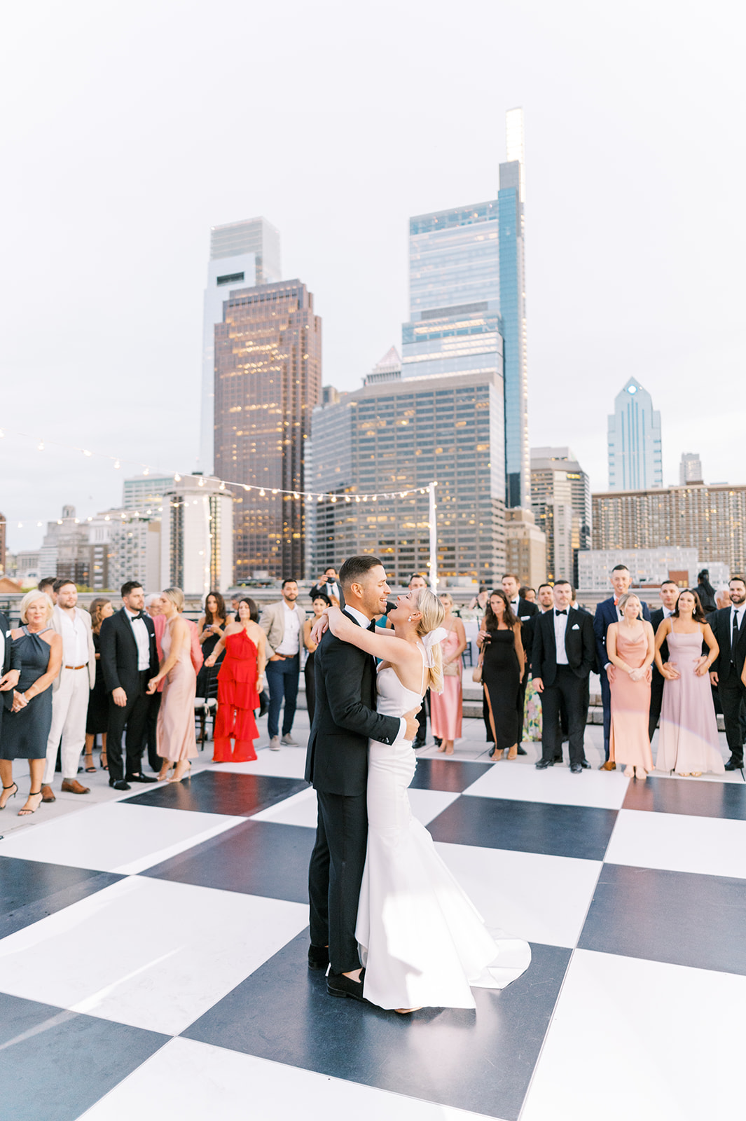 bride and groom have their first dance on the rooftop of the Free Library of Philadelphia with the city skyline