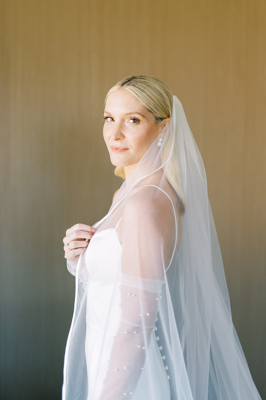 chic bride peers over her sheer white veil at The Logan in Philadelphia, PA