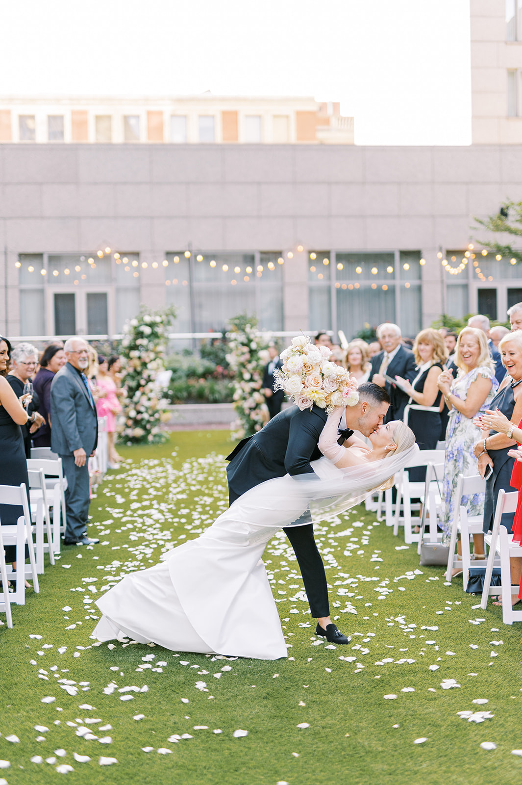 groom dramatically dips bride and gives her a kiss at chic outdoor summer wedding at the Logan in Philadelphia