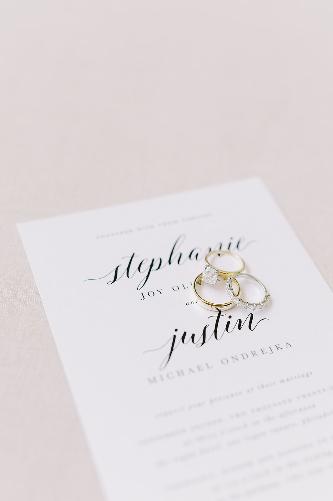 wedding rings sitting on simple and chic white and black wedding invitation