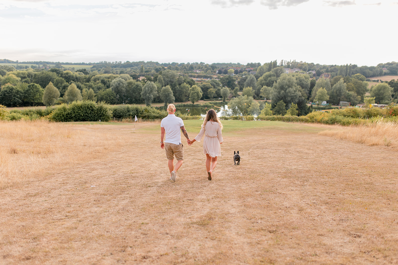 A couple and their French bulldog taking a walk during golden hour at The Three Lakes in Ware. 