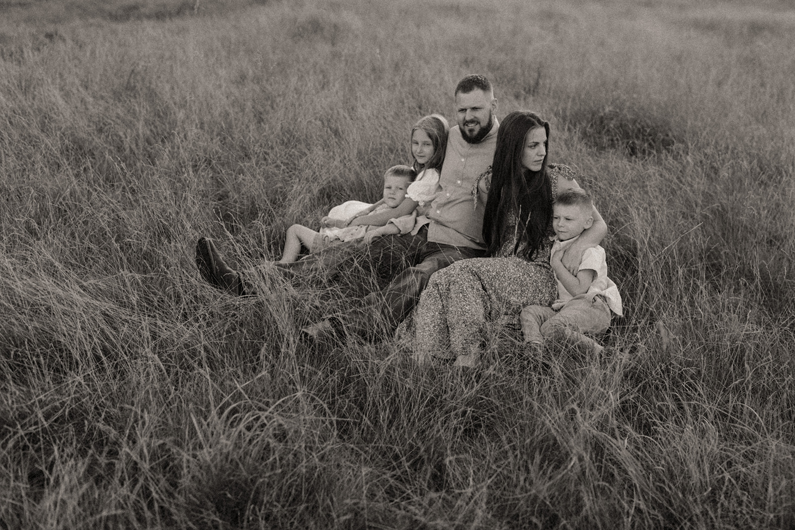 Family sitting in a field embracing