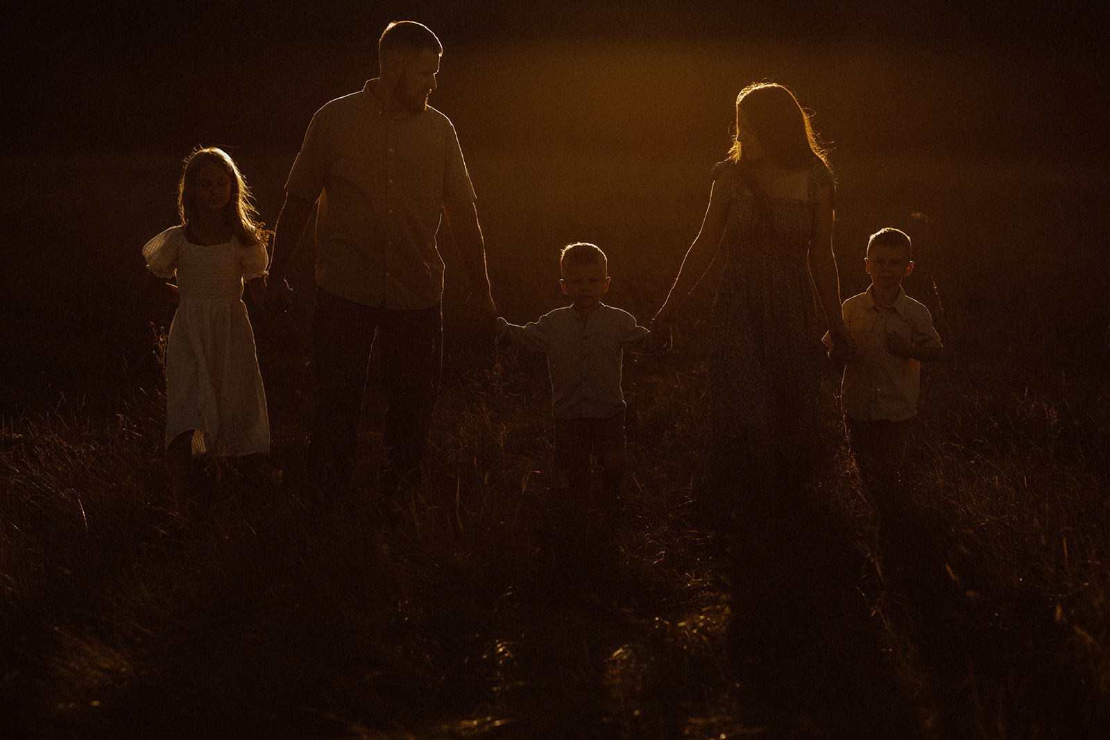 Family walking through a field at sunset