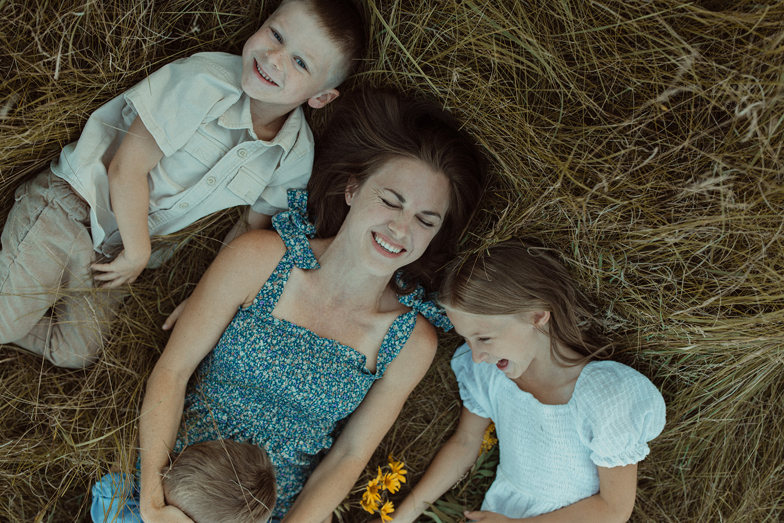 Mom with kids laying in grass laughing