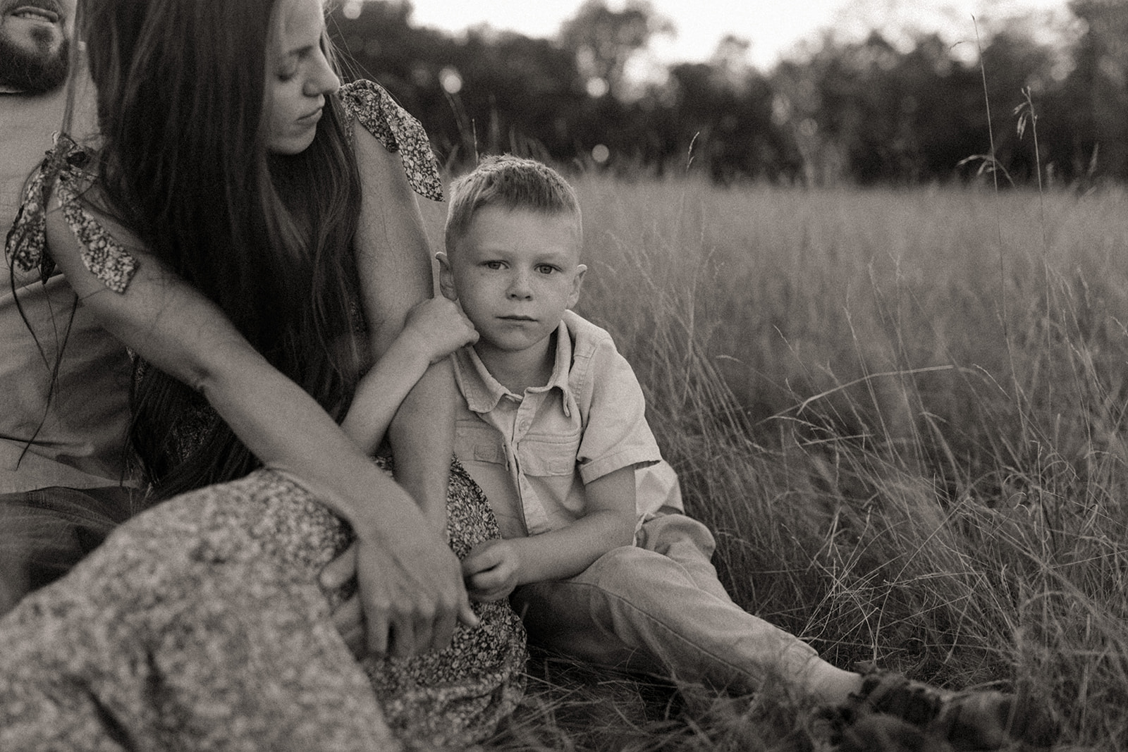 Mom and son sitting in a field at sunset