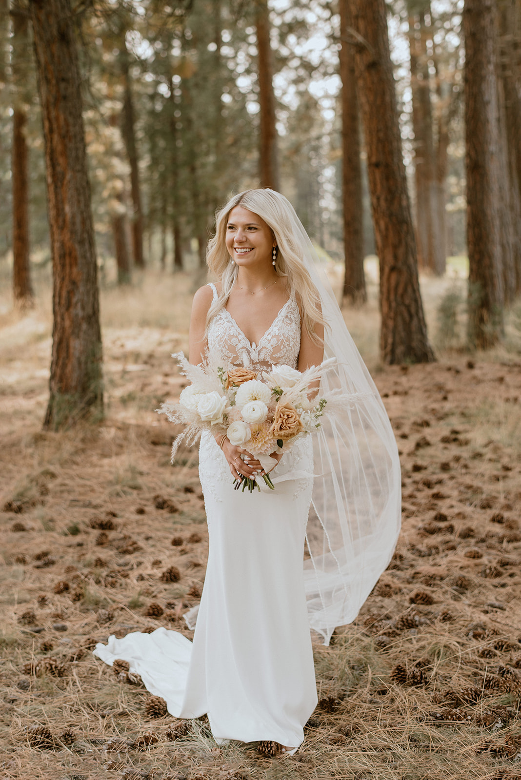 Bride with boho wedding bouquet with toffee roses and white dahlias, and a long white veil in the wind