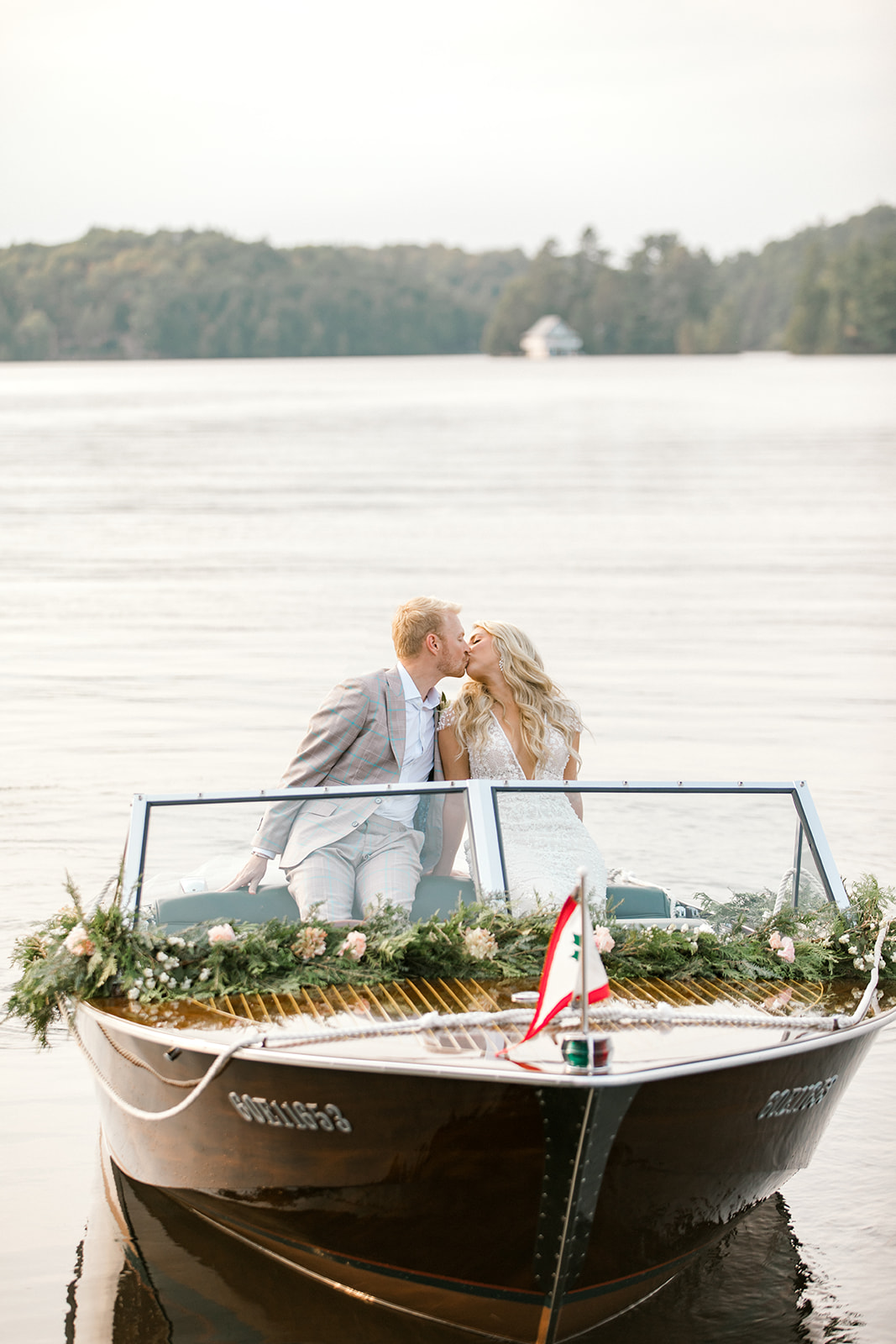 Couple kisses in a boat adorned in flowers during wedding reception in Port Carling, Muskoka