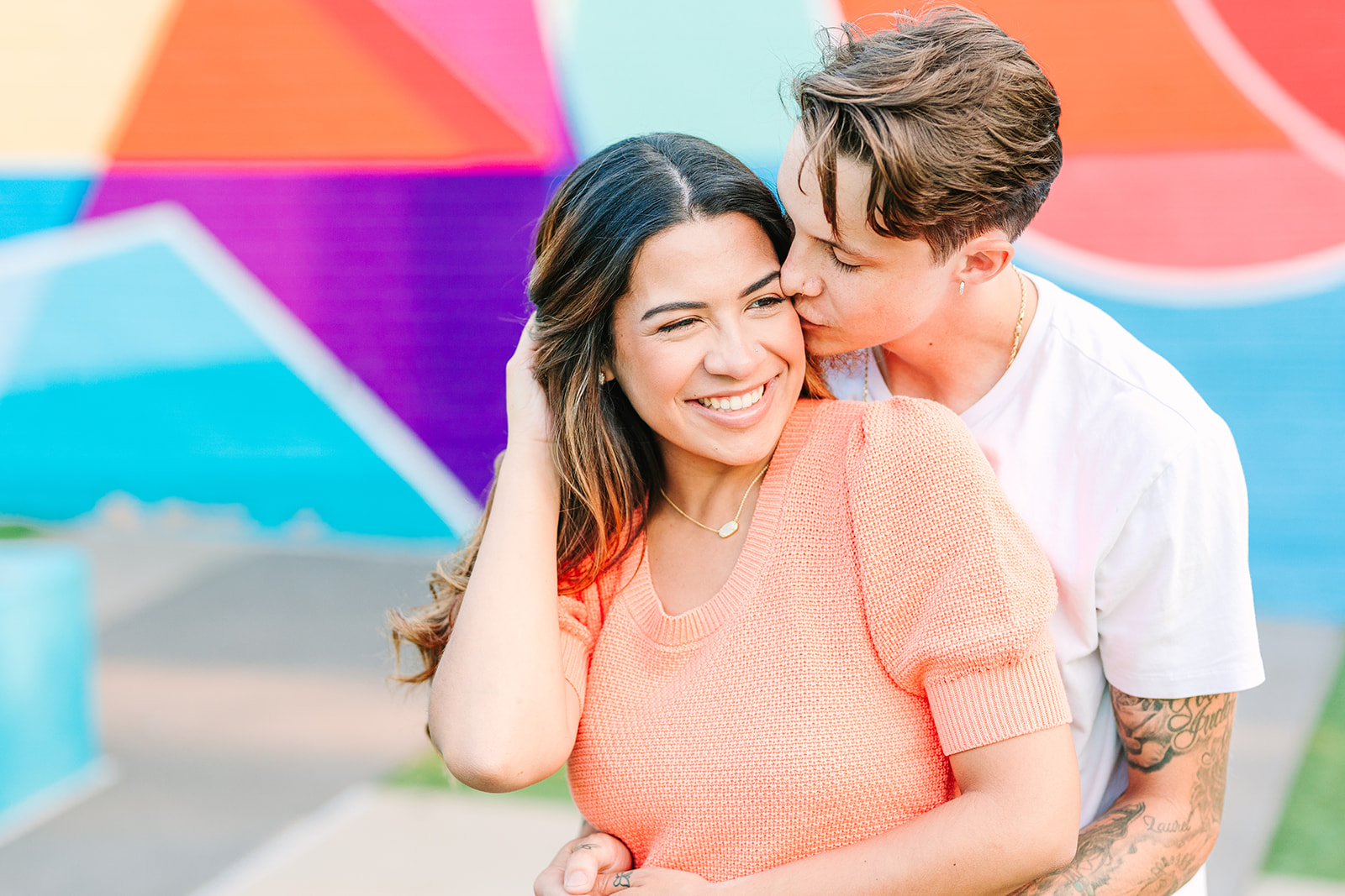 Couple engagement session in downtown Raleigh, North Carolina in front of the colorful mural at the Marbles Kids Museum