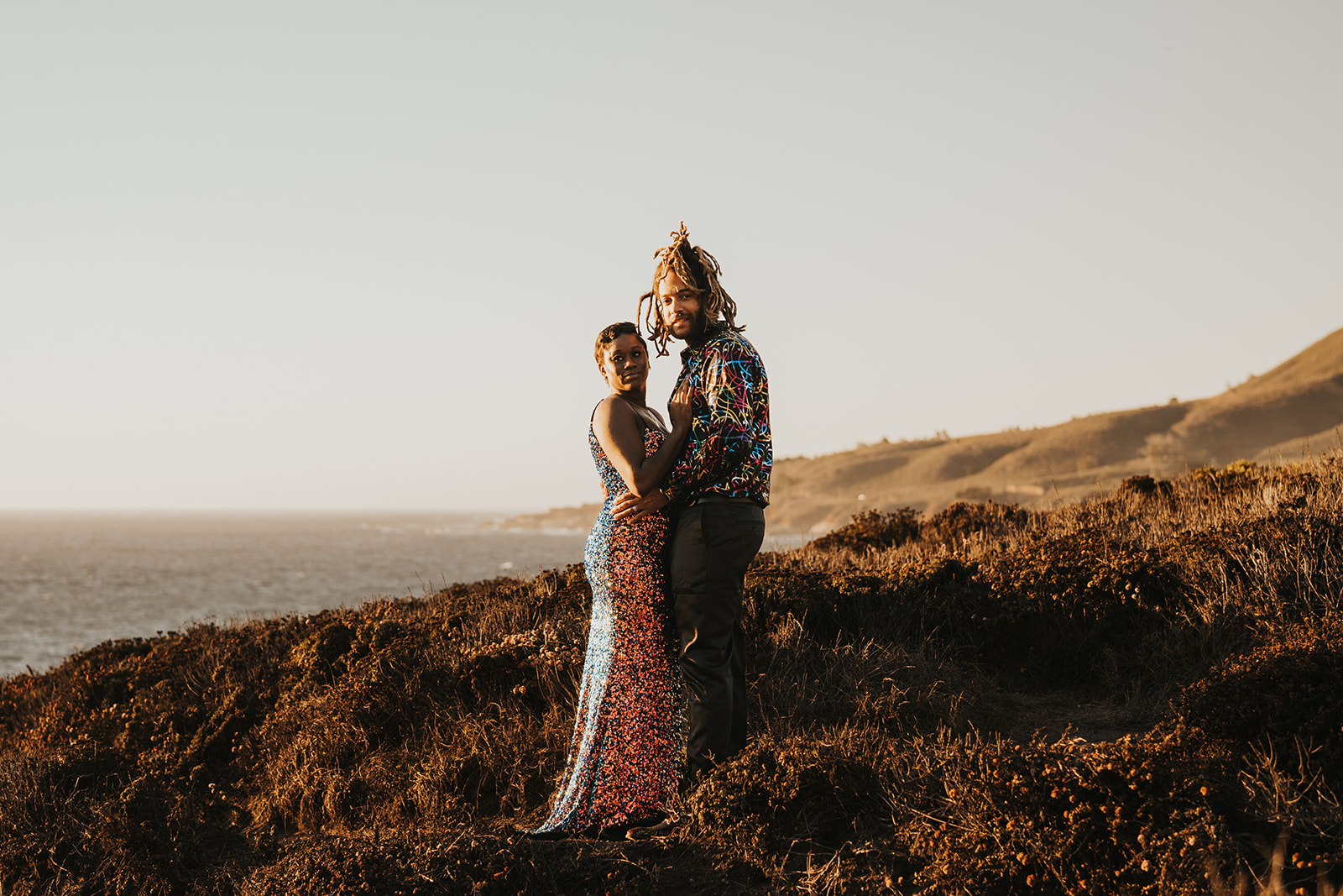 Couple stands on cliff overlooking ocean in big sur california