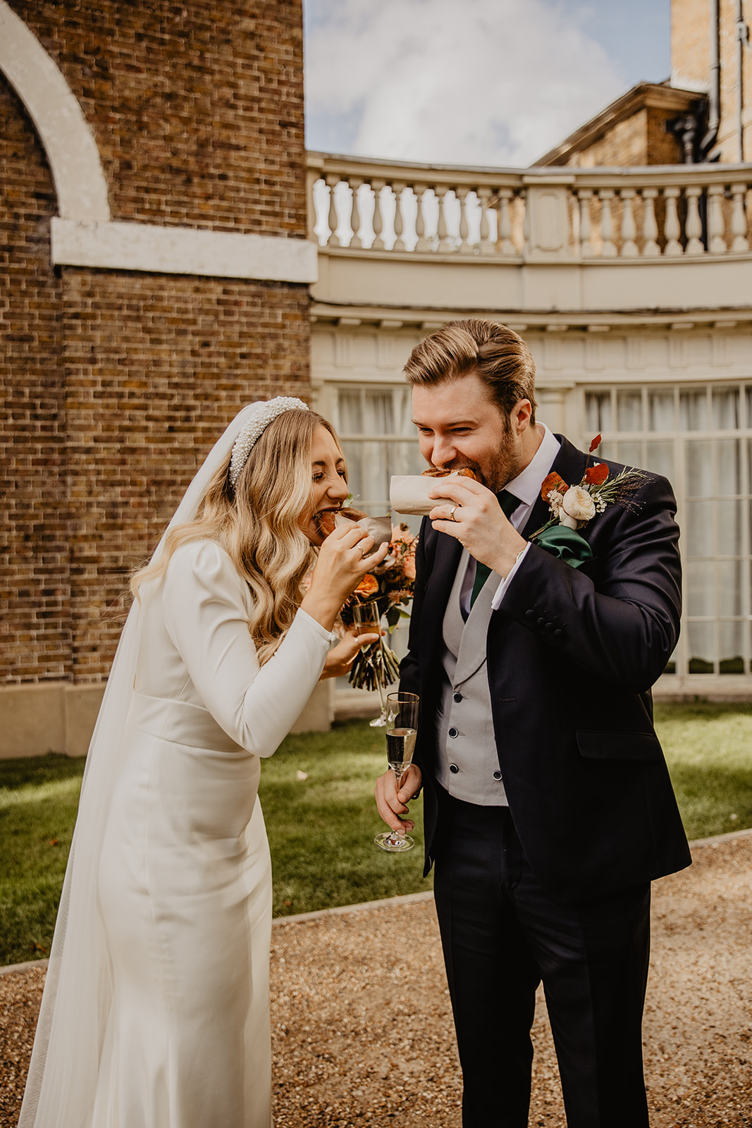Bride and Groom enjoying food at a Hampton Court House Wedding. By Olive Joy Photography