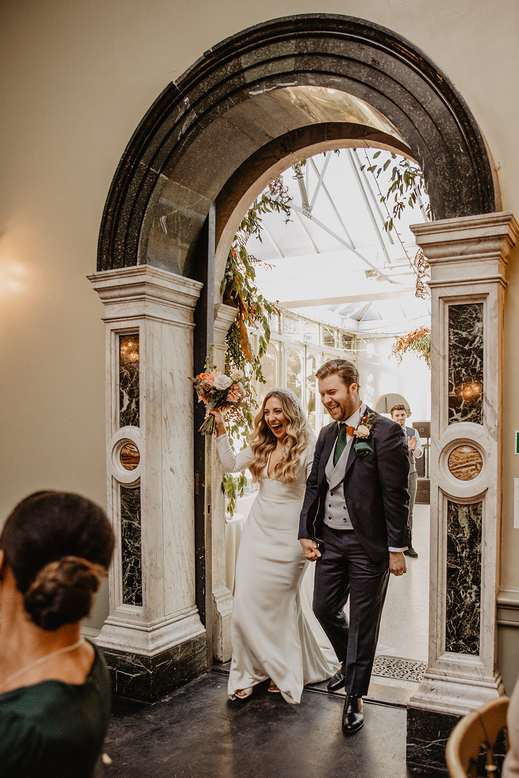 Bride and Groom entering reception at Hampton Court House on their Wedding Day. By Olive Joy Photography