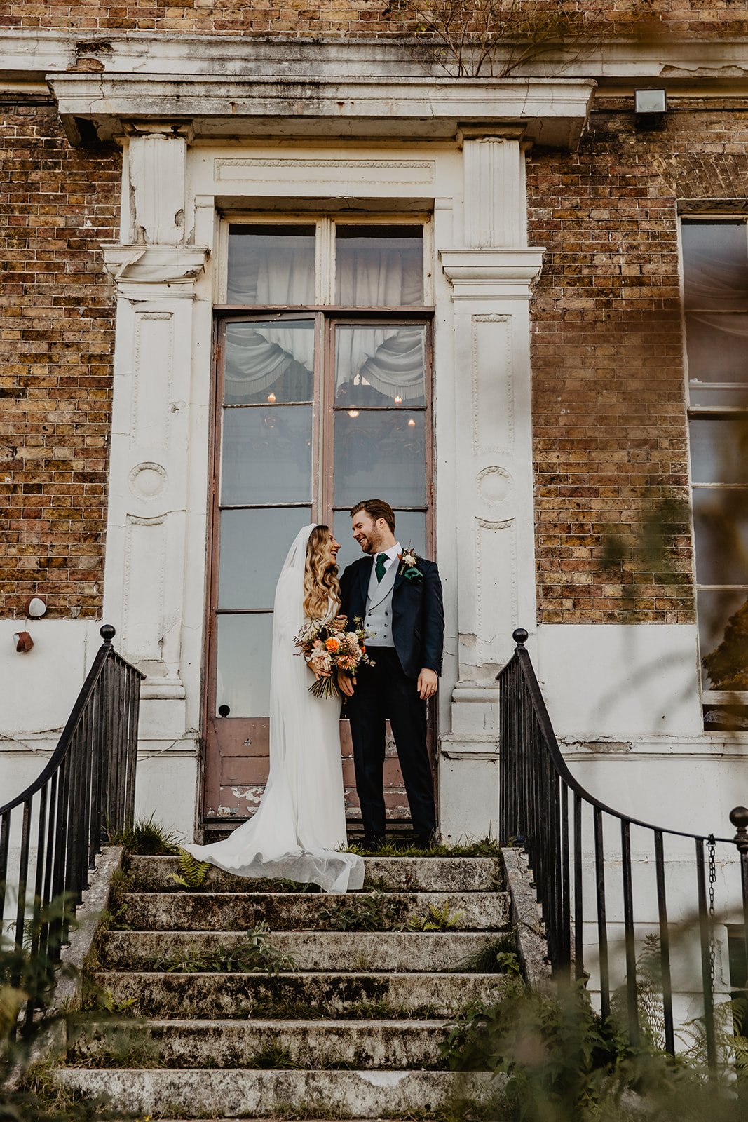Bride and Groom in front of Hampton Court House on their Wedding Day. By Olive Joy Photography