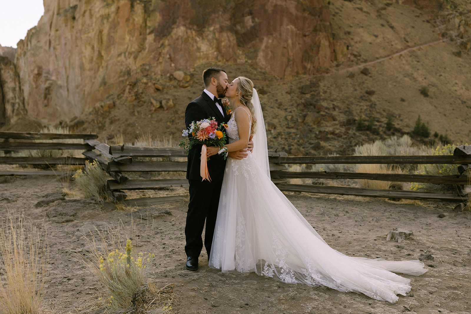 a couple just after getting married kissing at smith rock in their wedding attire