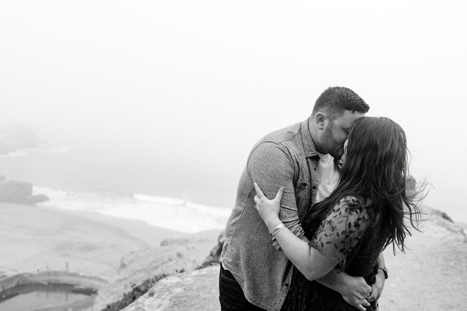 black and white A couple celebrates their engagement in the fog at Lands End San Francisco CA