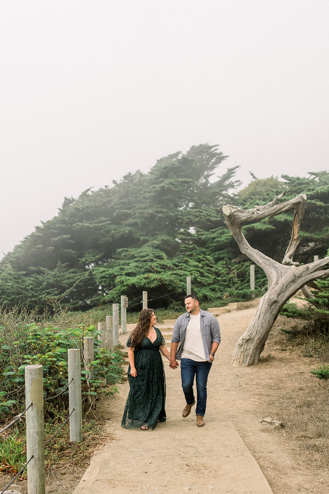 A couple celebrates their engagement in the fog at Lands End San Francisco CA