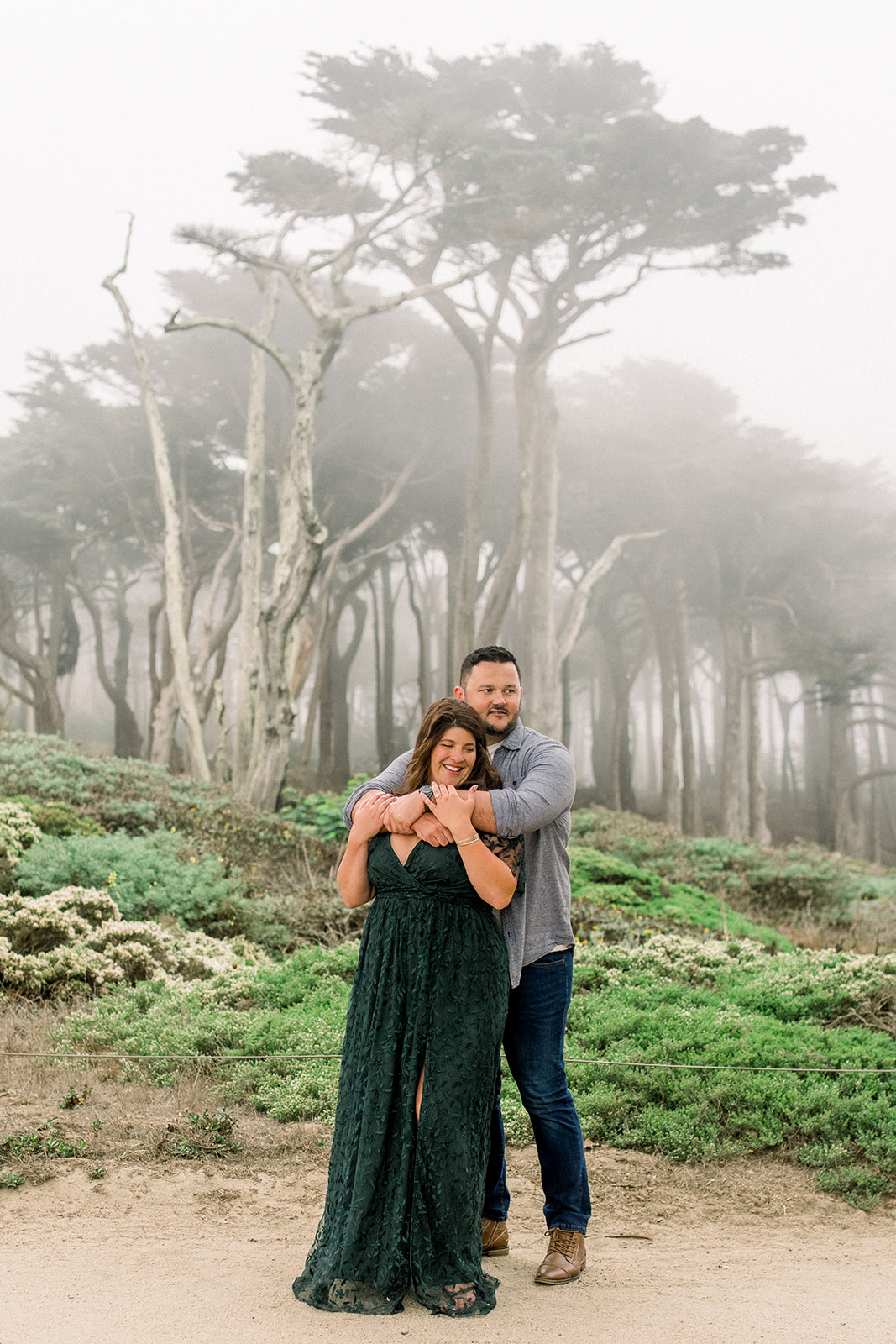 Cypress trees in fog A couple celebrates their engagement in the Cypress trees in fog at Lands End San Francisco CA
