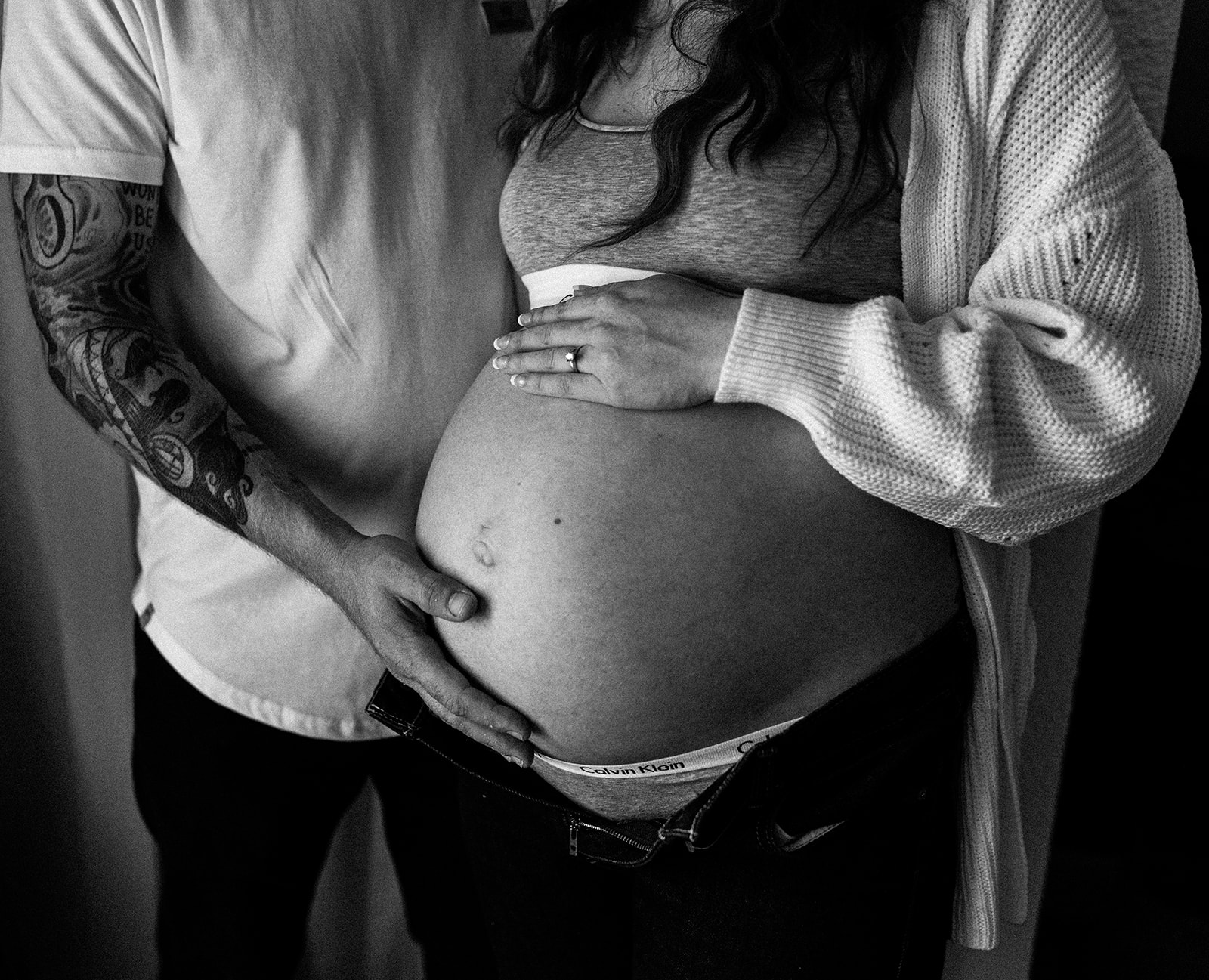 intimate moment of hands on belly at farmhouse maternity session