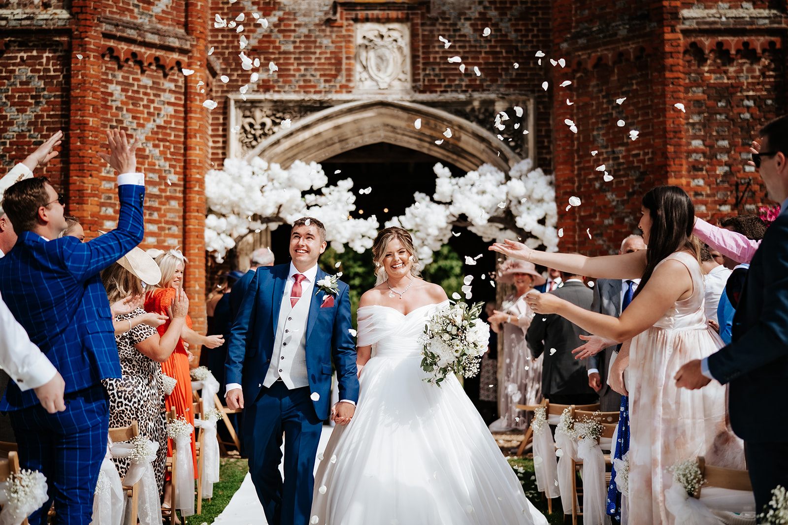 couple walk through confetti at Leez priory wedding venue in Essex