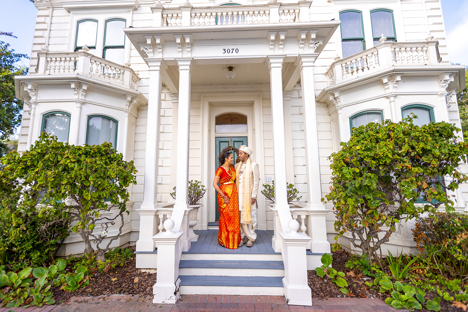 Bay Area Indian Wedding Venues Renstorff House provides a backdrop for indian bride and groom posins on doorstep.