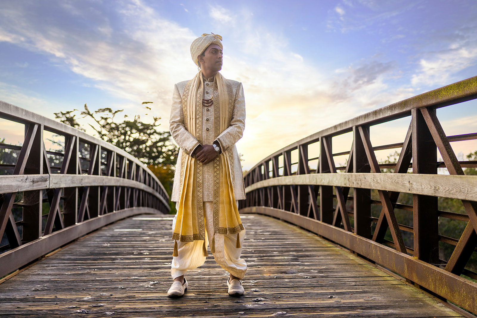 Groom poses on a bridge looking pensive with a dramatic sky in the background in the Bay area wedding venue.