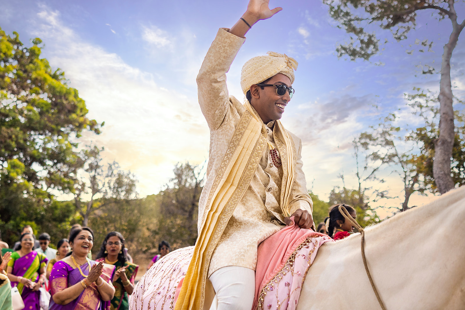 Groom waives to onlookers while riding a horse at Bay Area Indian Wedding Venue, Renstorff house.