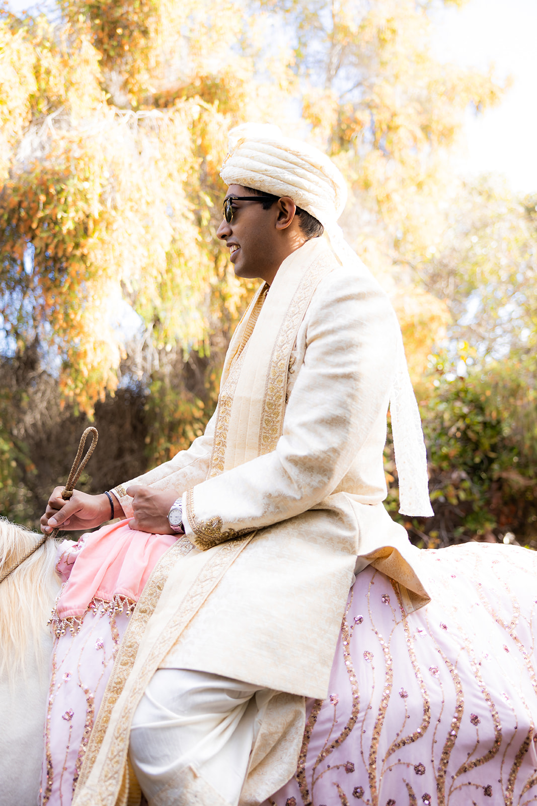 Indian groom rides on top of a horse.