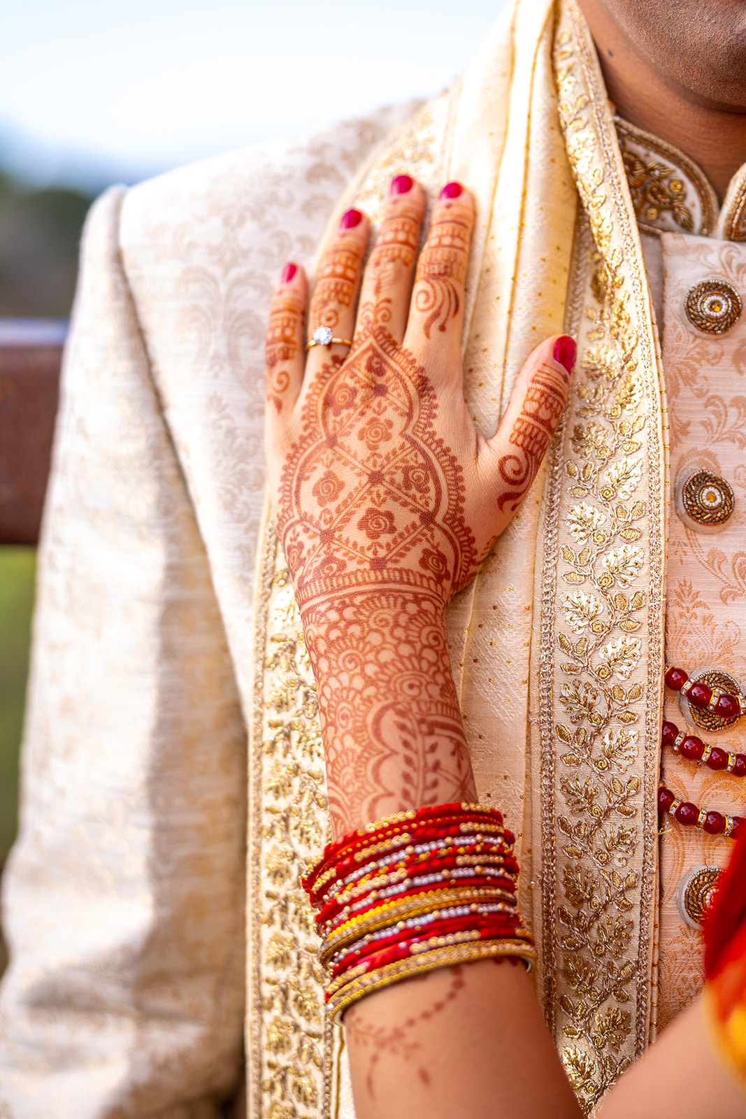Indian wedding bride's hand with henna on groom's chest.