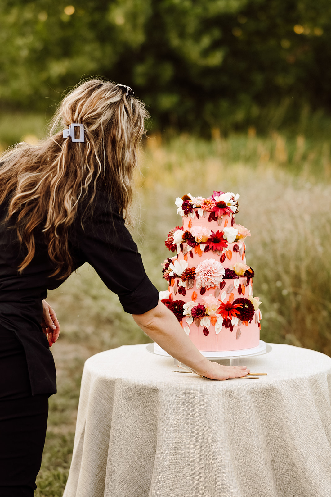 Wedding vendor placing pink wedding cake on a table 
