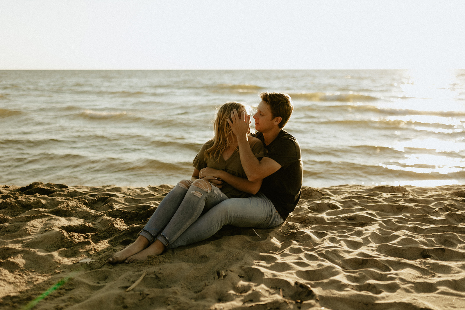 A couple sitting in the sand at Saugatuck Dunes State Park in Michigan