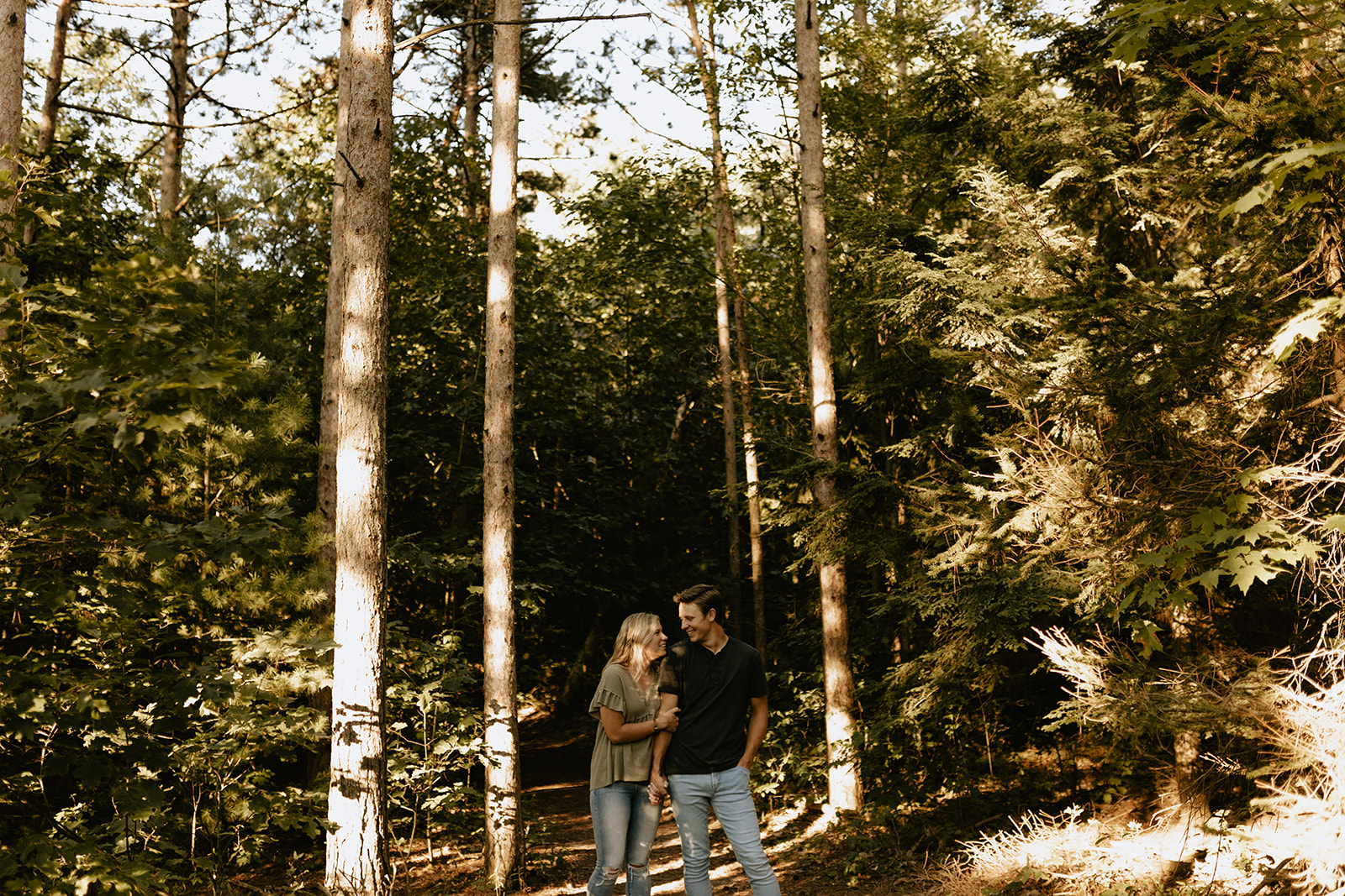 A couple holding hands in the woods at Saugatuck Dunes State Park in Michigan 