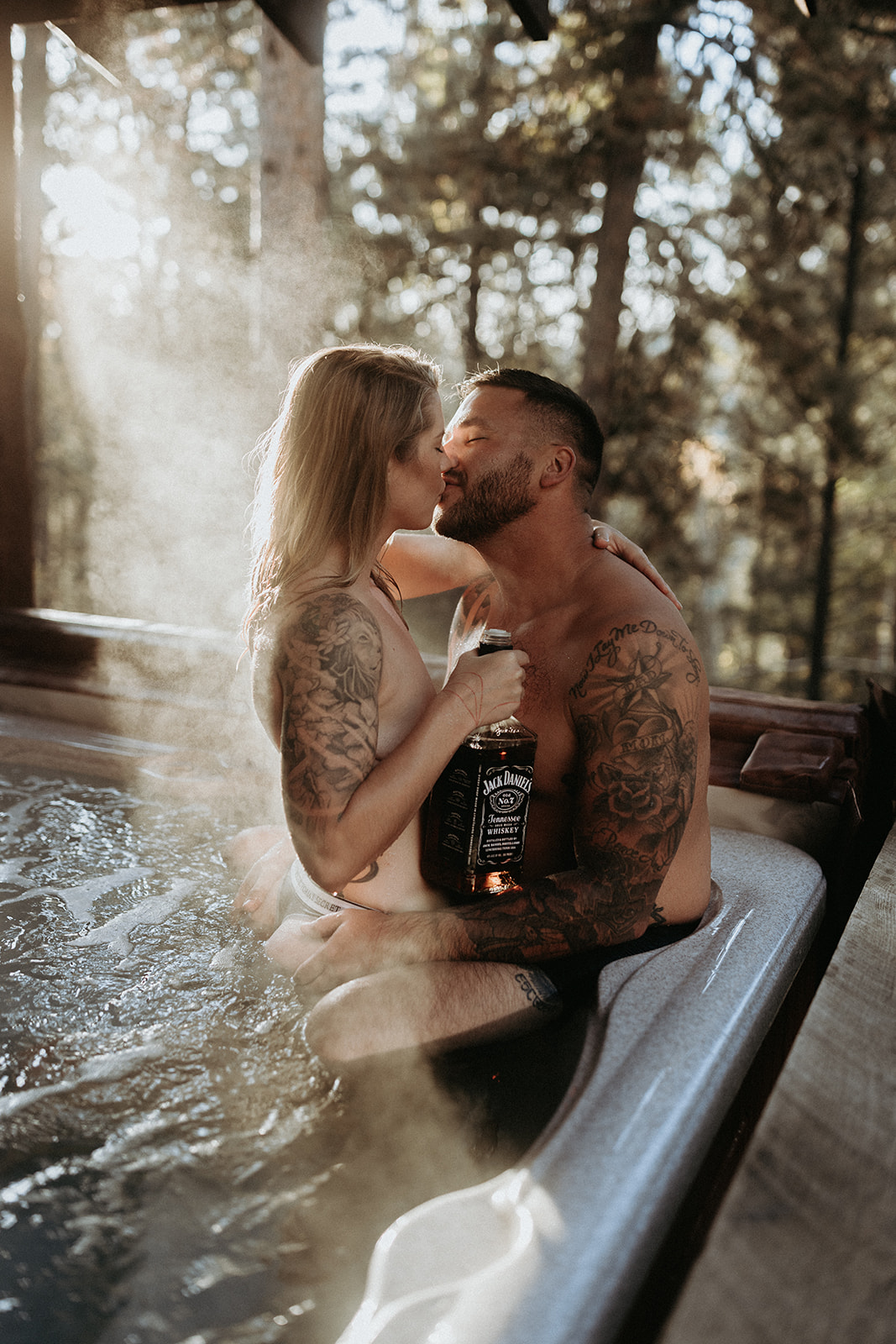 A couple kissing in a hot tub while the girl holds a bottle of Jack Daniel's whiskey.
