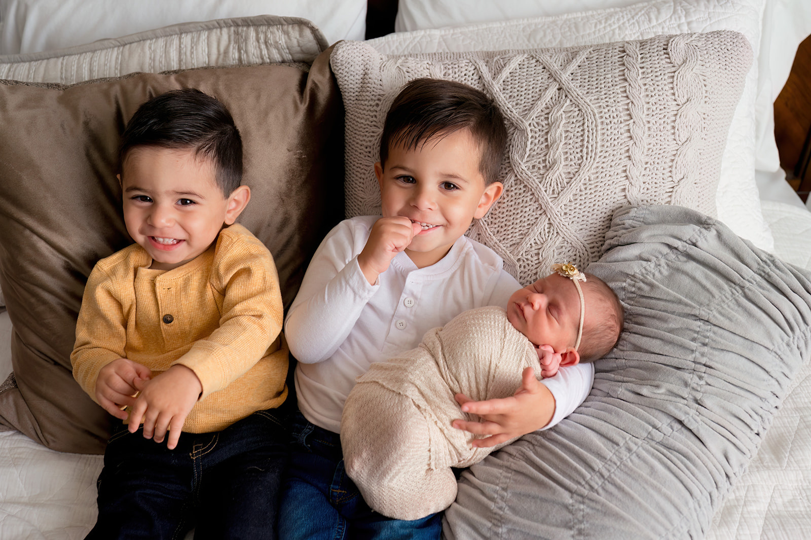 newborn baby girl being held older brothers in loveland photography studio bedroom set