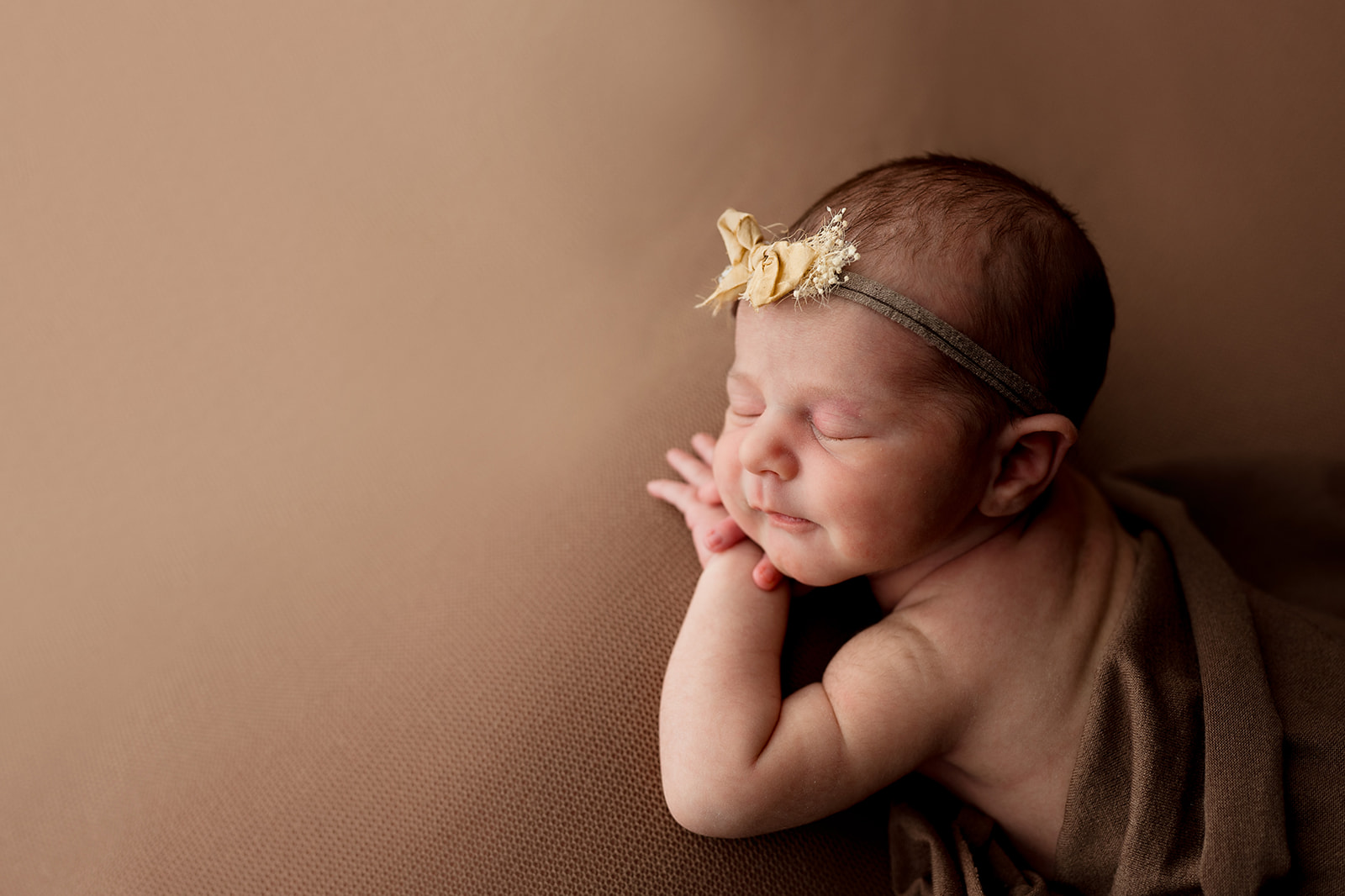Profile of sleeping newborn resting her cheek on her hand