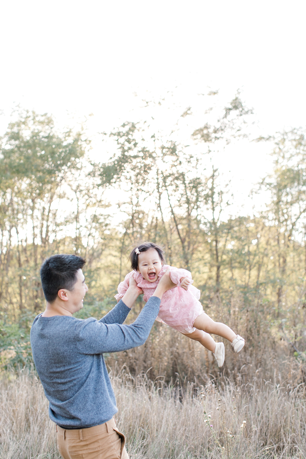 Father tosses daughter in the air with big laughter during a family photoshoot in Toronto