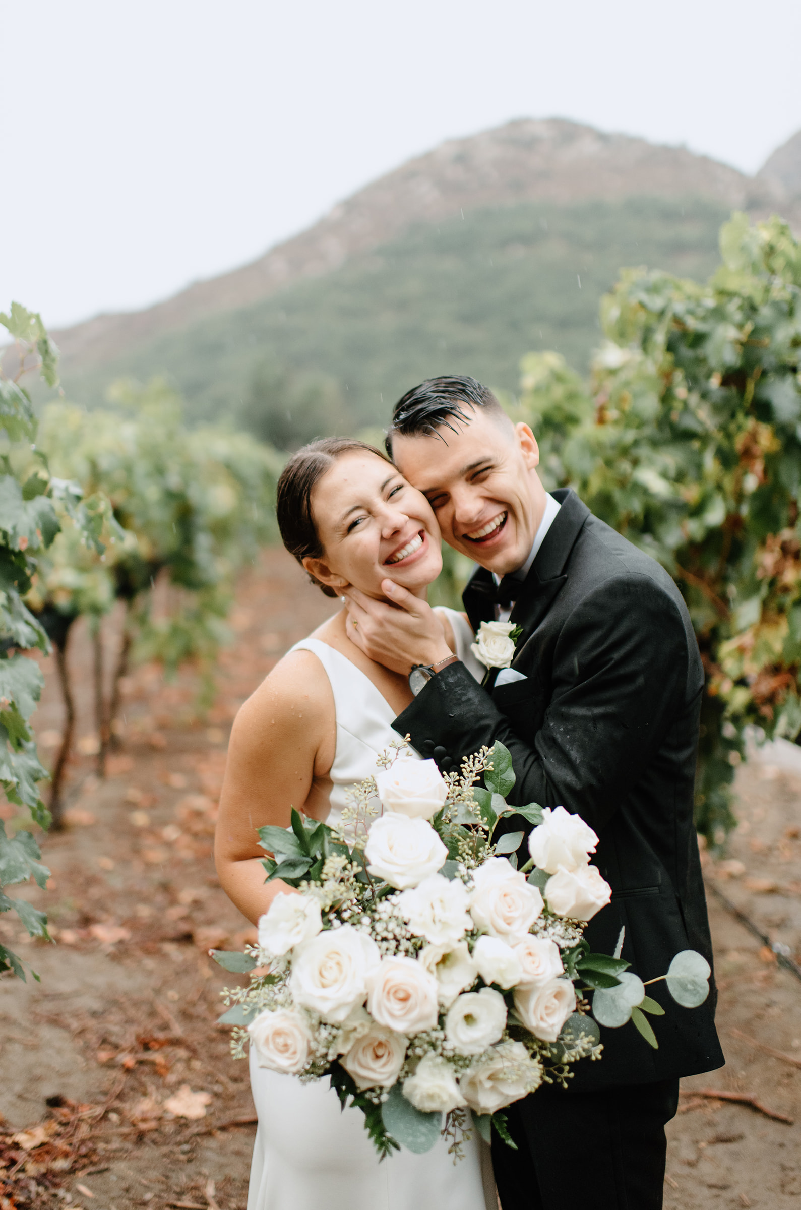 Bride and groom smile together after their rainy wedding ceremony at Rancho Guejito venue