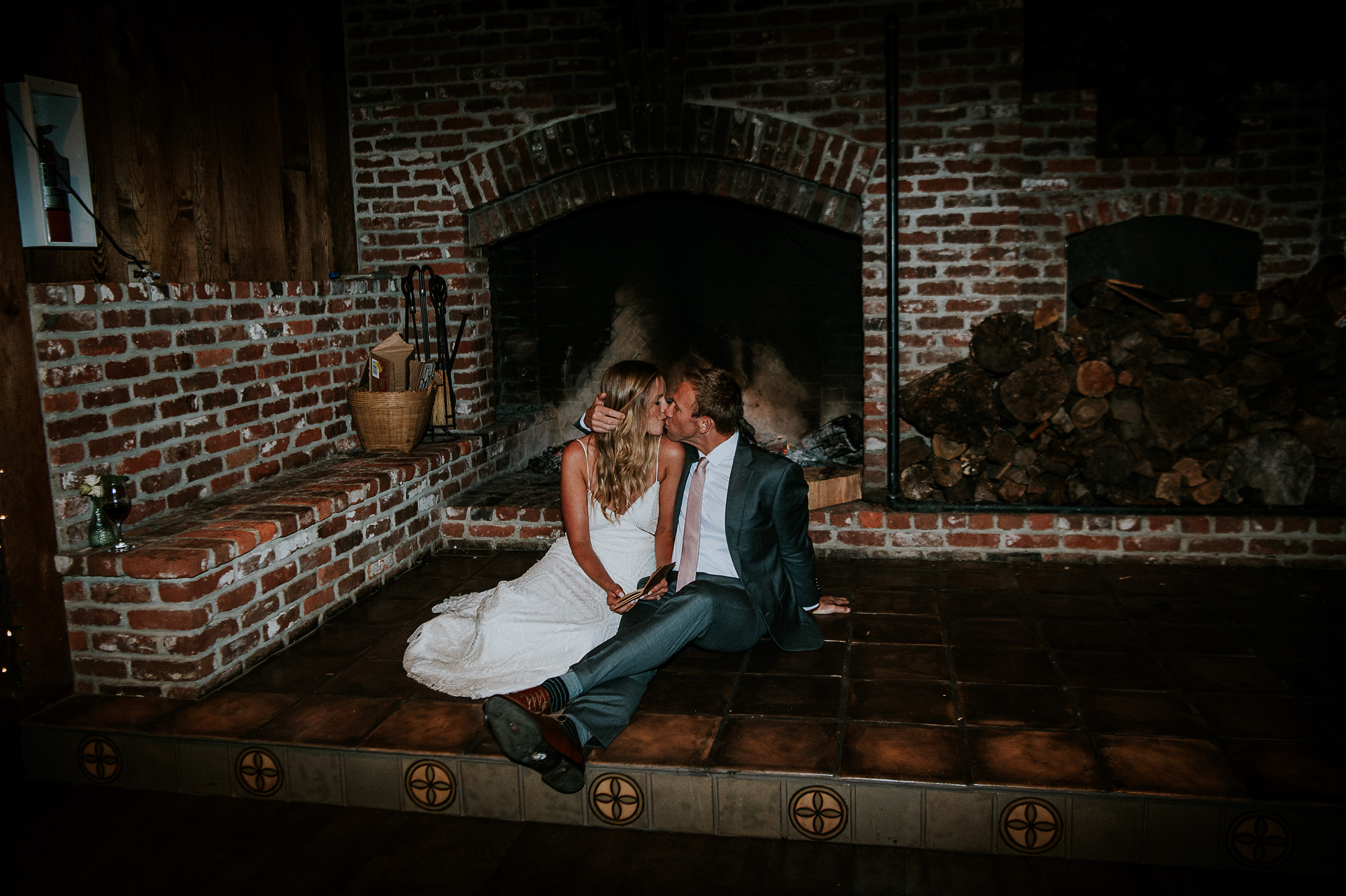 bride and groom sitting in front of the large open fireplace