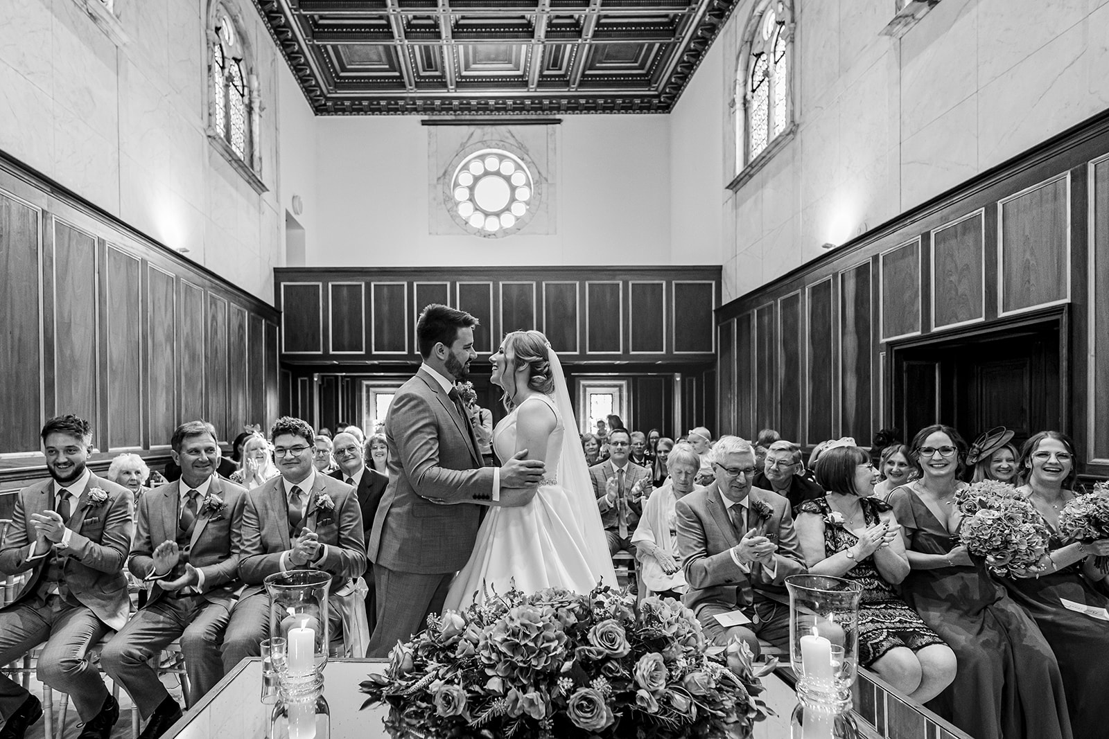 Black and white bride and groom embrace during wedding ceremony at Bourton Hall