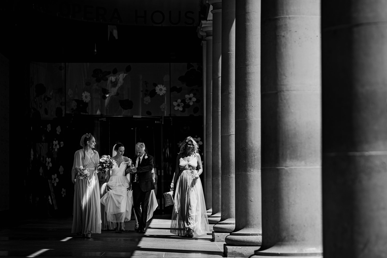 Bride walking through the columns of the Royal Opera House.