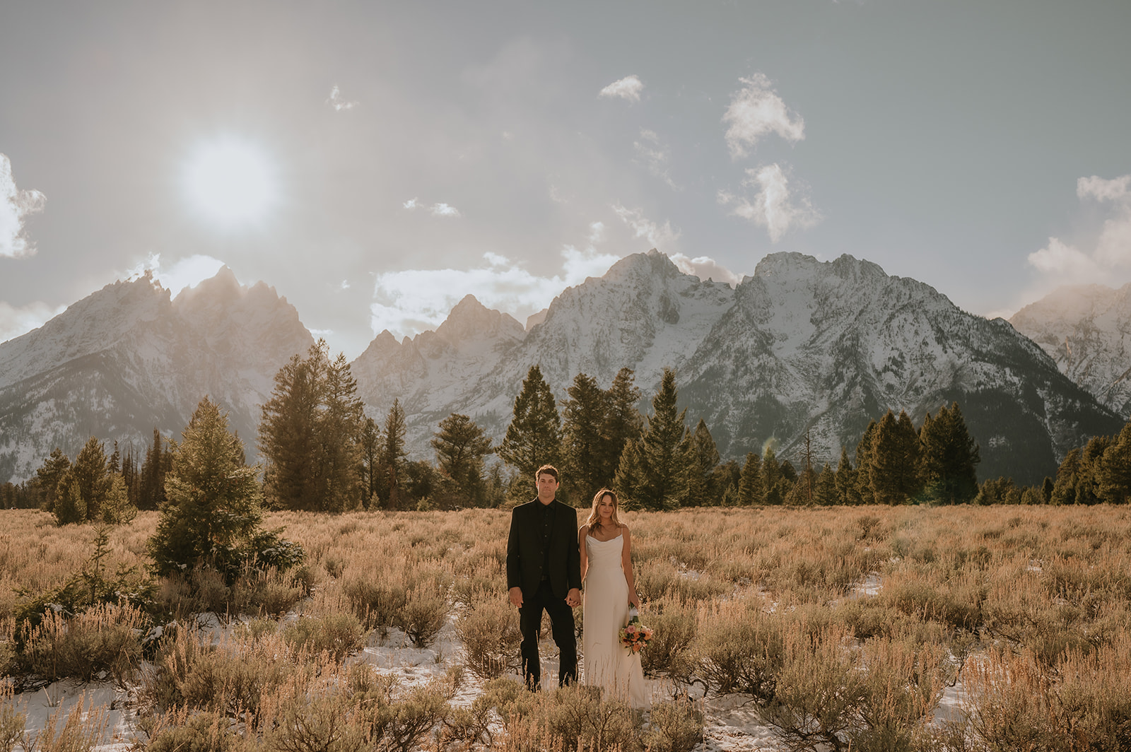 Couple stands in front of Tetons Mountain range at sunset after they eloped