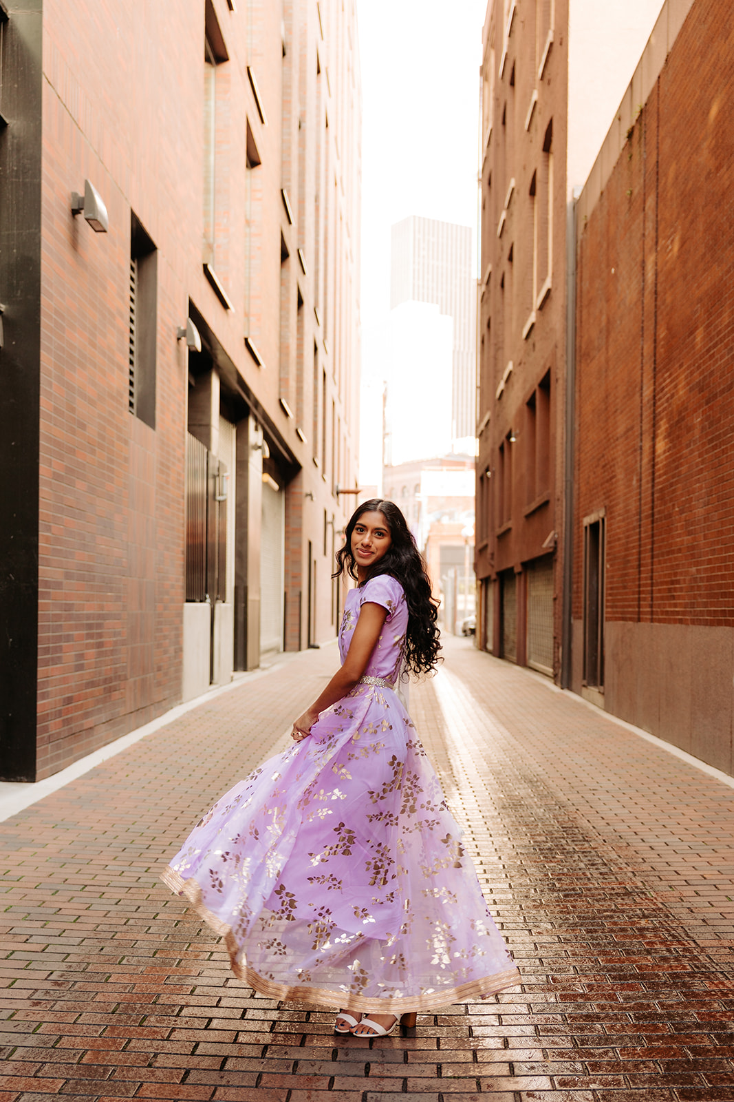 An edgy photo of an ethnic high school senior girl posing in front of a brick alleyway in Pioneer Square, Seattle.