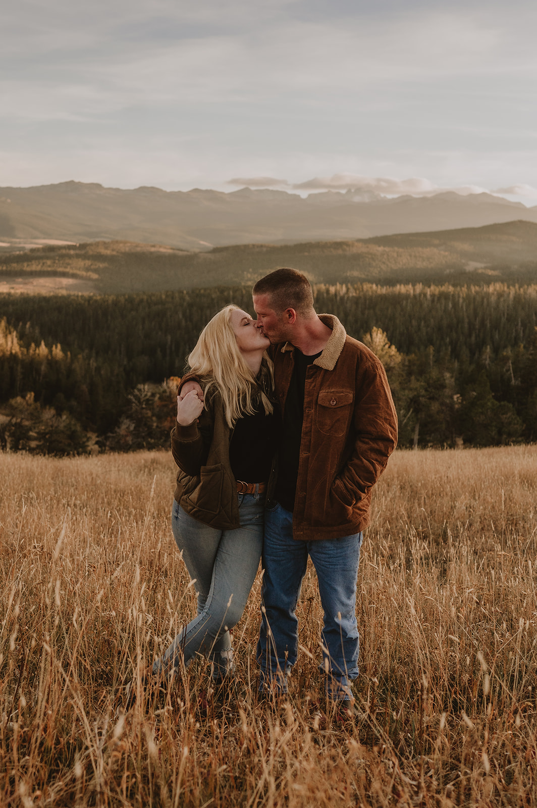 A couple walking together through the Bighorn Mountains with arms around each other, kissing