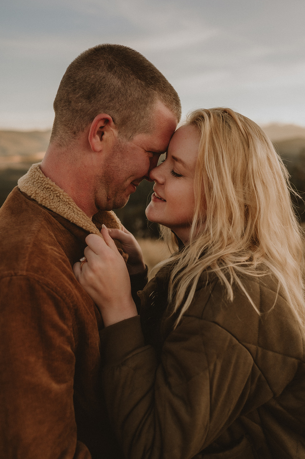 An engaged couple stands close, face to face, for an intimate portrait by Wyoming photographer Kaylie Sirek